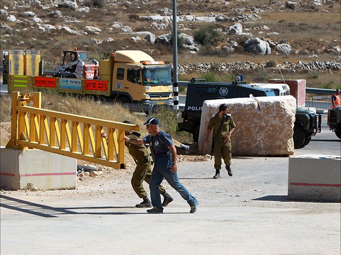 epa03796160 Israeli soldiers and a security personnel open the gate of a check-point in the West Bank city of Hebron 21 July 2013. The Israeli government reopened a main road at the southern West Bank district of Hebron after a 12-year closure, a Palestinian Authority liaison official said. EPA/ABED AL HASHLAMOUN