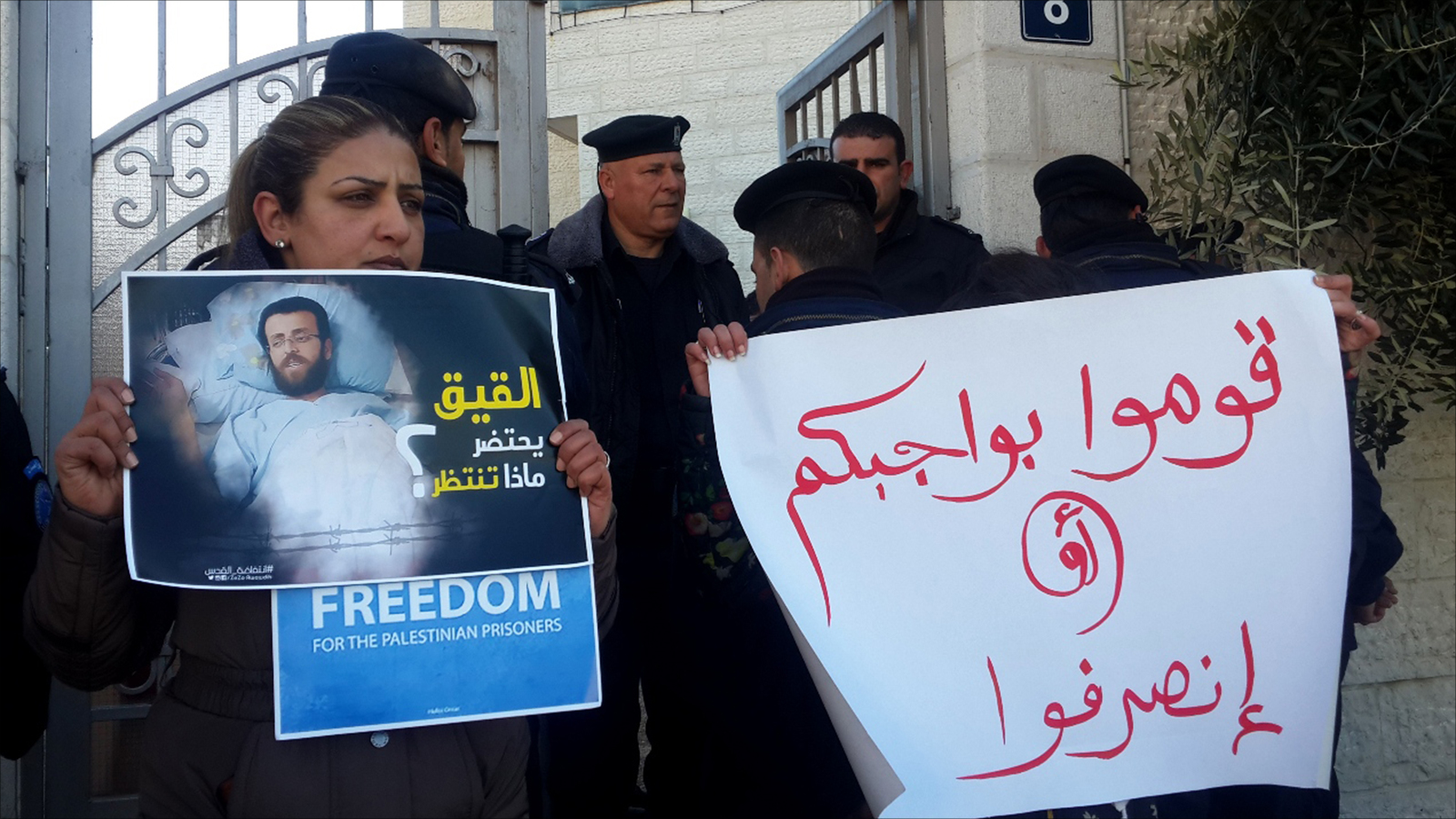 ‪ناشطة فلسطينية تحمل ملصقا للأسير القيق بعد أن تدهورت حالته الصحية جراء إضراب مستمر منذ 77 يوما‬ (الجزيرة)